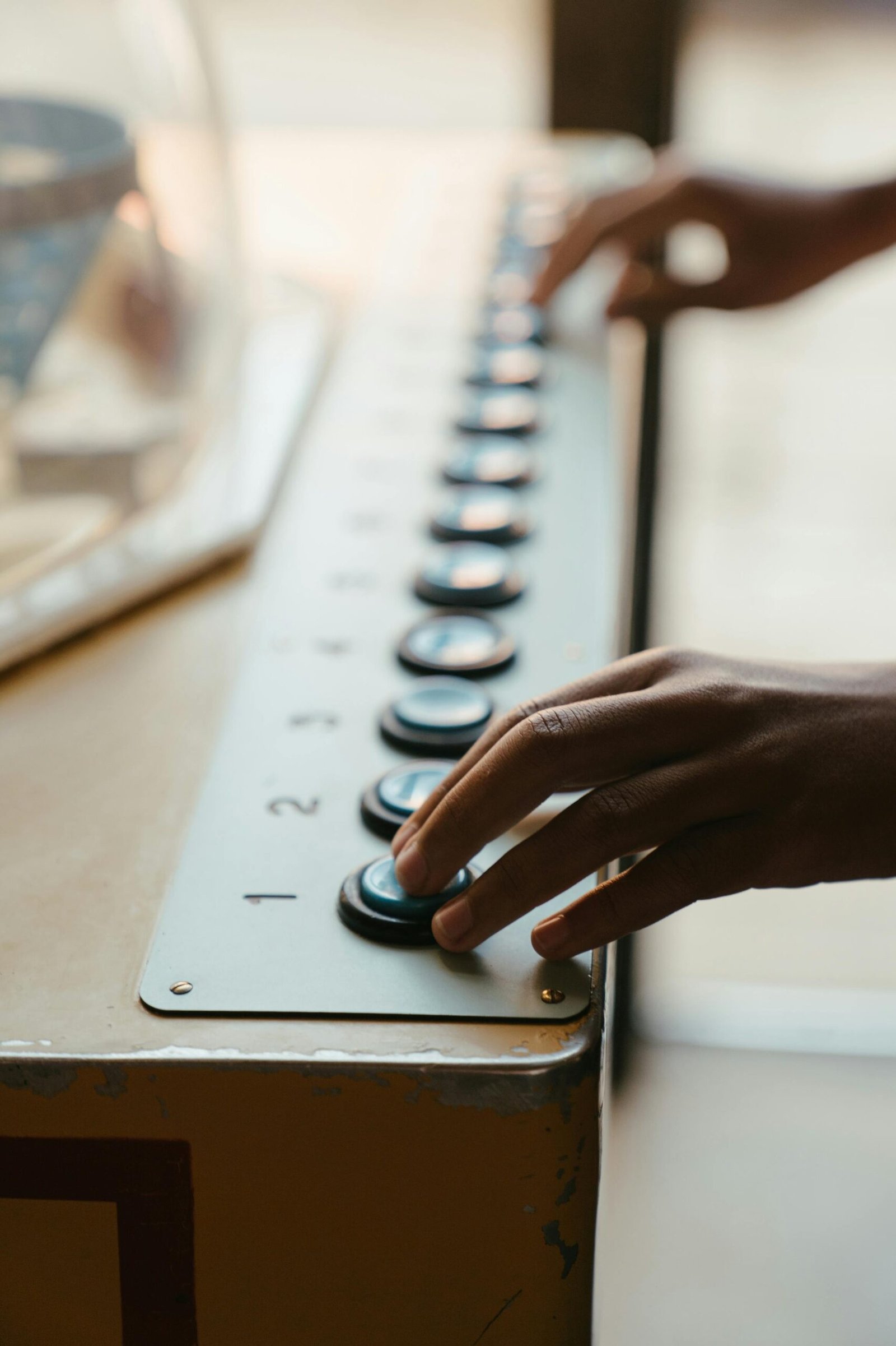 Close-up of hands operating a vintage arcade button panel with numbered keys.